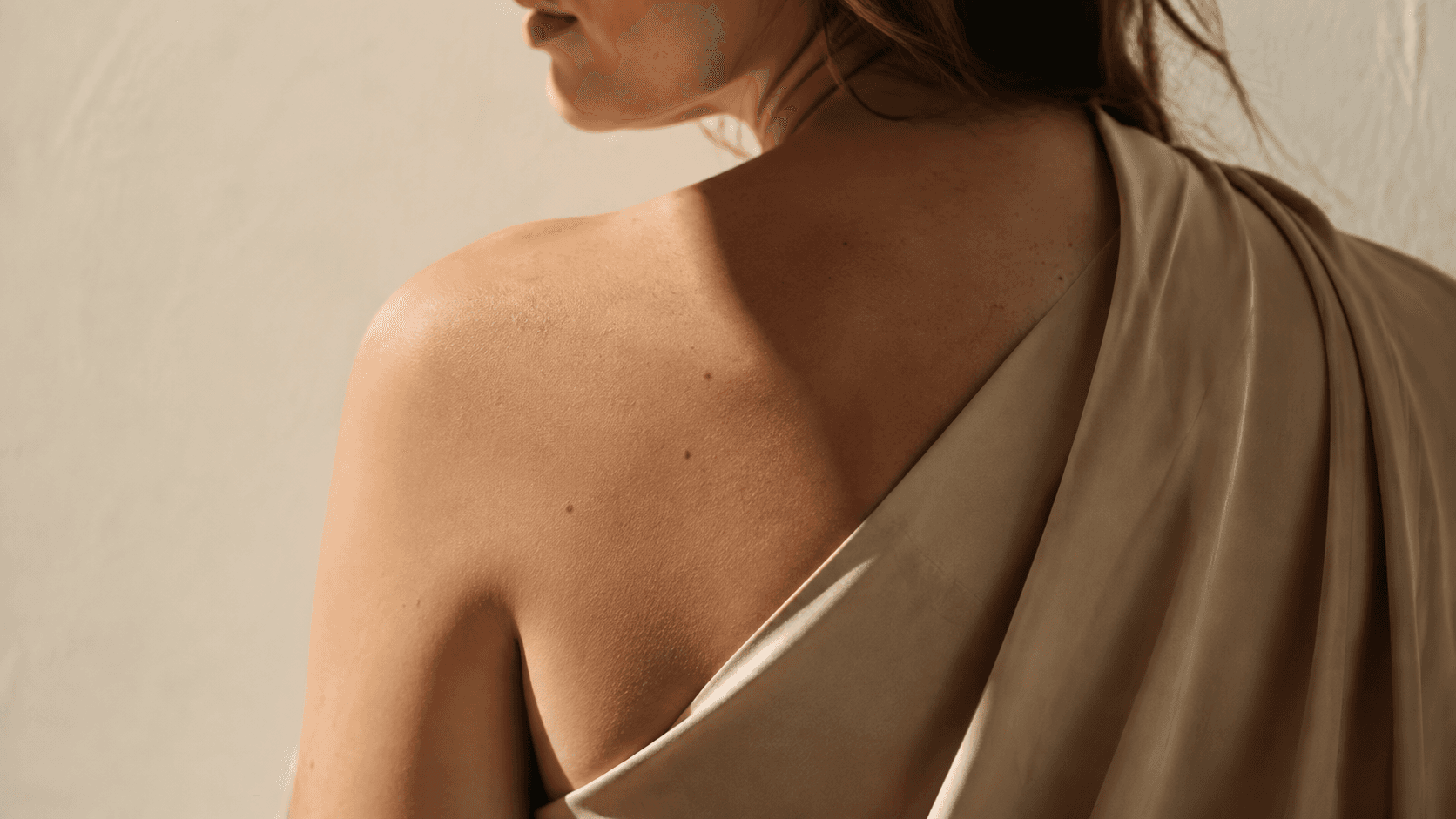 Woman’s shoulder and upper back exposed to warm sunlight, illustrating areas commonly affected by cumulative sun exposure.